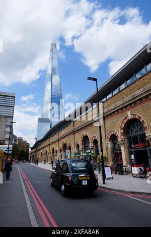 Londra - 06 10 2022: Taxi di Londra che passa a St Thomas St a Bermondsey con il grattacielo Shard sullo sfondo Foto Stock