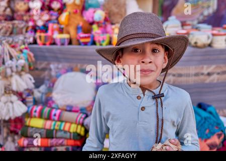 Ritratto di un ragazzo latino con cappello da cowboy che guarda la macchina fotografica con un volto sorpreso a una fiera di Jujuy, Argentina. Foto Stock