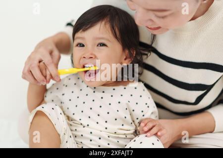 madre che lavava i denti delle sue figlie piccole. buon bambino con lo spazzolino Foto Stock