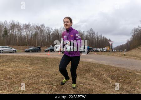 Grodno, Bielorussia - 25 marzo, 2023: Forte ragazza caucasica adolescente indossare abbigliamento sportivo che corre attraverso una foresta durante l'esercizio in esterni orienteering Gr Foto Stock