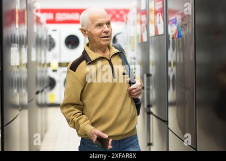 Pensionato Senor MAN che acquista un frigorifero nello showroom del negozio di elettrodomestici Foto Stock