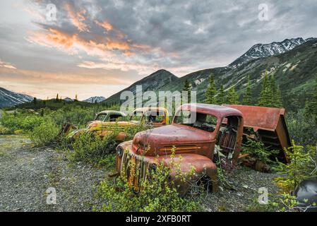 Vecchio camion d'epoca arrugginito, annidato nella natura selvaggia con sfondo montano estivo. Preso nel territorio dello Yukon, Canada. Foto Stock