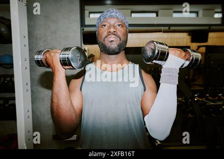Uomo afroamericano che solleva manubri pesanti, si è concentrato sulla tecnica di esercizio Foto Stock