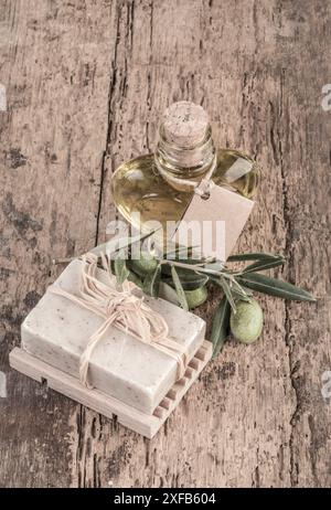 Sapone naturale e olio d'oliva in una bottiglia a forma di cuore su un tavolo di legno Foto Stock