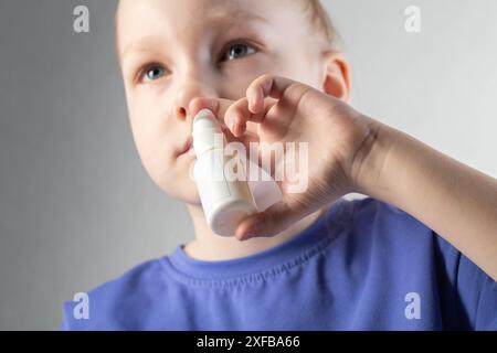 Una ragazza spruzza uno spray contro il naso che cola e la congestione nasale nei suoi seni. Trattamento di sinusite e sinusite, spray antimicrobico. Foto Stock