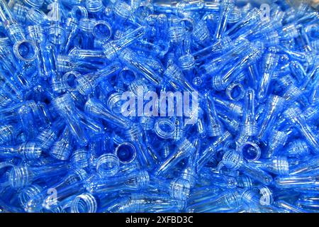 Pila di bottiglie di plastica blu nella linea di produzione al PET di produzione, prima che le bottiglie soffiino nella macchina per la soffiatura alla fabbrica di acqua per bevande. Foto Stock