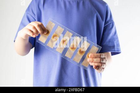Un bambino tiene tra le mani un pacchetto con un cerotto adesivo per i calli principali Foto Stock