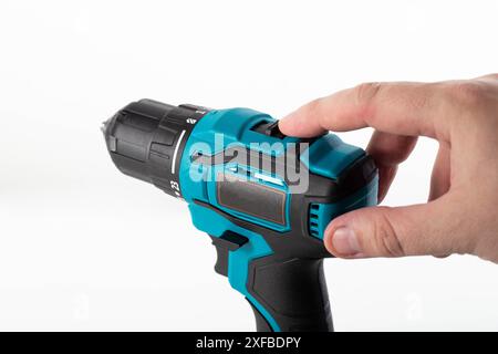 Il dito di un lavoratore commuta l'interruttore del senso di rotazione su un trapano avvitatore, primo piano, settore industriale Foto Stock