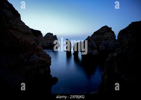 Ora blu davanti all'alba, rocce nel mare, Ponta da Piedade, Lagos, grotte, scogliere, oceano Atlantico, Algarve, Portogallo Foto Stock