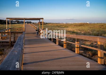 Donna che legge un cartello informativo sul lungomare, sul lungomare, sul lungomare, sul sentiero costiero, sulla spiaggia di Meia Praia, Lagos, Oceano Atlantico, luce serale, Algarve Foto Stock