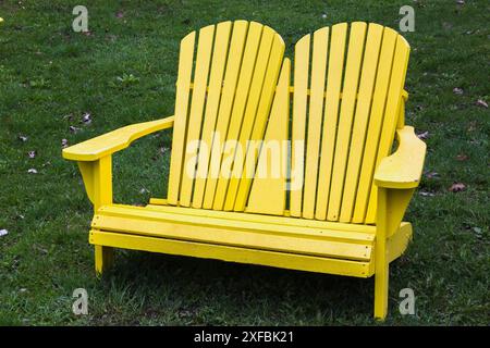 Sedie Adirondack a due posti in legno dipinto di giallo su prato verde in primavera, Giardino Botanico di Montreal, Quebec, Canada Foto Stock