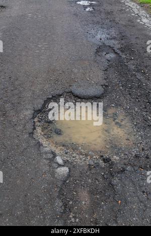 Buche riempite di acqua piovana su fondo stradale bagnato in asfalto nero in primavera, Montreal, Quebec, Canada Foto Stock