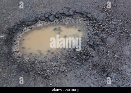 Buche riempite di acqua piovana su fondo stradale bagnato in asfalto nero in primavera, Montreal, Quebec, Canada Foto Stock