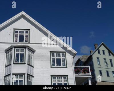 Una casa bianca in legno con molte finestre e vasi di fiori sul balcone sotto un cielo azzurro, haugesund, norvegia Foto Stock