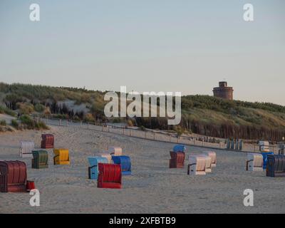 Sedie a sdraio davanti alle dune e un faro, atmosfera tranquilla la sera, juist, mare del nord, germania Foto Stock