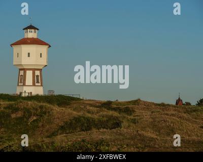 Un faro su una collina tra le dune, illuminato dalla luce soffusa del tramonto Foto Stock