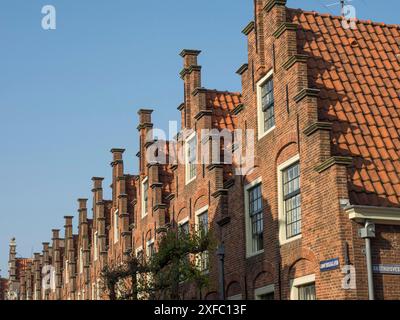Fila di edifici storici con suggestivi tetti di tegole rosse sotto un cielo azzurro Foto Stock