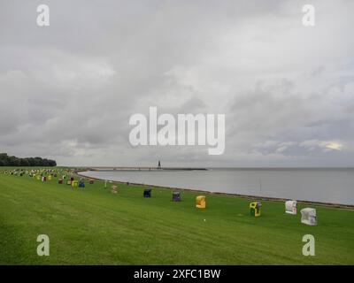 Sedie da spiaggia colorate su un grande prato vicino al mare sotto un cielo coperto, cuxhaven, germania Foto Stock