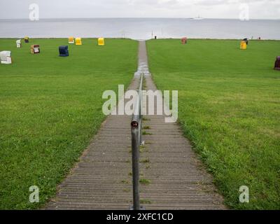 Un sentiero conduce alla costa con sedie a sdraio colorate su un prato verde, cuxhaven, germania Foto Stock