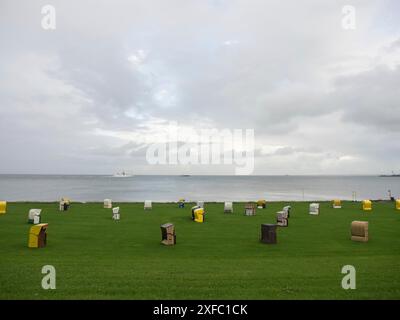 Sedie da spiaggia colorate si trovano in un prato sulla costa, il cielo è nuvoloso, cuxhaven, germania Foto Stock