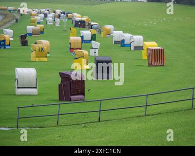 Colorate sedie da spiaggia sono sparse su un prato verde, circondato da gabbiani, cuxhaven, germania Foto Stock