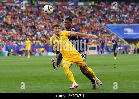 Valentin Mihaila rumeno (a sinistra) e Denzel Dumfries olandesi si battono per il pallone durante la partita UEFA Euro 2024, nella gara di 16 partite alla Munich Football Arena di Monaco, Germania. Data foto: Martedì 2 luglio 2024. Foto Stock