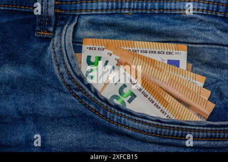 Tre banconote da 50 euro piegate incastrate nella tasca anteriore dei jeans blu Foto Stock