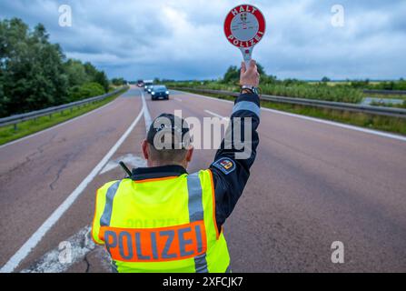 Sanitz, Germania. 2 luglio 2024. Un agente di polizia dirige i veicoli al parcheggio di Speckmoor sulla superstrada A20 per un controllo a tema del traffico incentrato sul "traffico delle vacanze". Con l'inizio della stagione delle vacanze in Germania, la polizia del Meclemburgo-Vorpommern si sta concentrando in particolare sul traffico delle vacanze per tutto il mese di luglio. Principalmente camper e roulotte sono controllati per la sicurezza stradale e il peso. Crediti: Jens Büttner/dpa/Alamy Live News Foto Stock