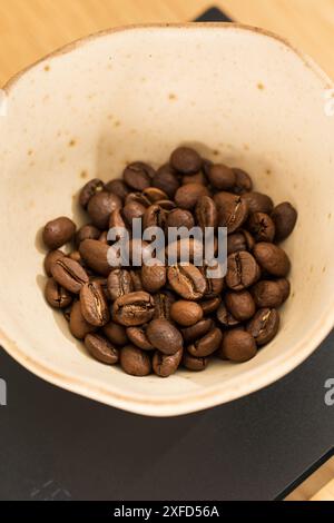 Chicchi di caffè tostati pesati con bilancia digitale sul tavolo Foto Stock