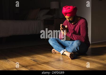 Meditare sul pavimento, uomo in turbante che pratica consapevolezza a casa, copiare spazio Foto Stock