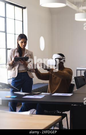 Utilizzando il visore VR, l'uomo interagisce con l'ambiente virtuale mentre la donna osserva Foto Stock