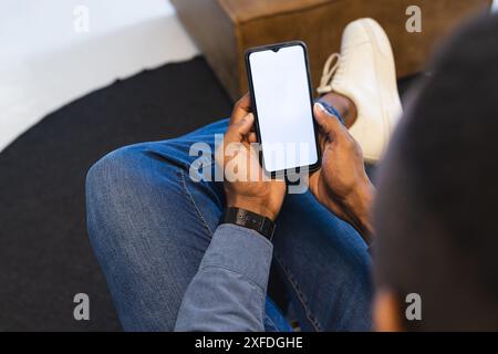 Tenere in mano lo smartphone, l'uomo in un abbigliamento casual che controlla i messaggi mentre è seduto, copiare lo spazio Foto Stock