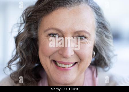 Donna anziana sorridente con capelli grigi che guarda la fotocamera, ritratto ravvicinato Foto Stock