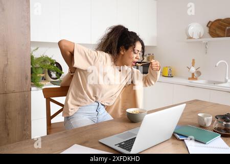 Affrettati donna d'affari afroamericana a fare colazione e a mettere il blazer in cucina Foto Stock