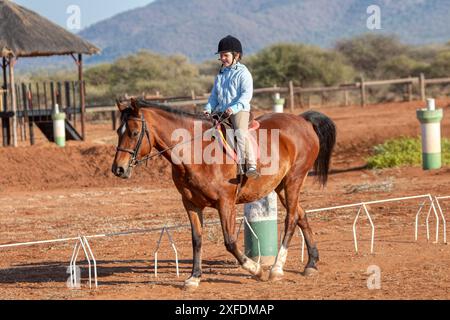 piccola ragazza che cavalca e si allena su un cavallo, casco da equitazione nero, mattina fredda Foto Stock