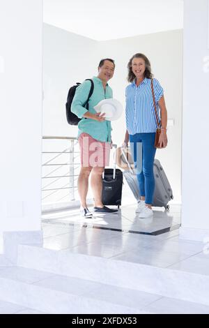 Coppia senior con bagagli in preparazione per le vacanze, sorridente e pronta a viaggiare Foto Stock