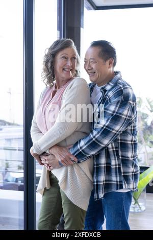 La coppia senior si abbraccia e sorride, godendo del tempo di qualità insieme in casa Foto Stock