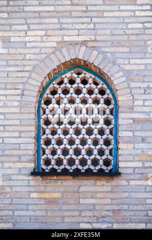 Finestra con un reticolo di piastrelle di ceramica nell'antica parete in mattoni della vecchia moschea musulmana Hazrati Imam in Uzbekistan Foto Stock