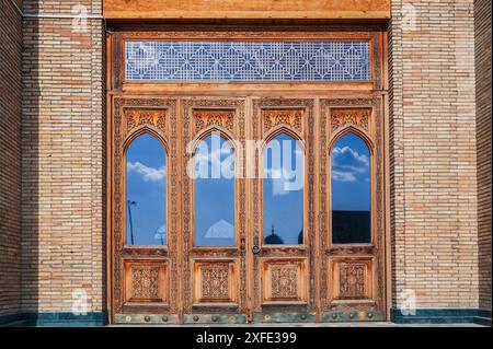 Vecchia porta in legno intagliato con vetro con motivi uzbeki all'antica moschea islamica di Hazrati Imam in Uzbekistan Foto Stock