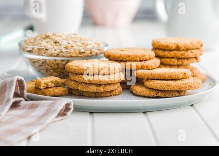 Gustosi biscotti con farinata d'avena e avena arrotolata su un tavolo bianco. Foto Stock