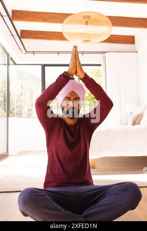 Meditare a casa, uomo in turbante che pratica yoga in camera da letto Foto Stock