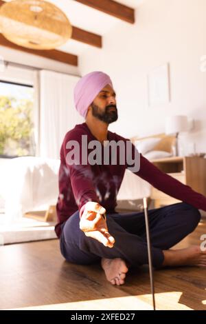 Meditando a casa, uomo in turbante che pratica consapevolezza con il bastone dell'incenso Foto Stock