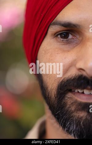 Primo piano di un uomo indiano con turbante rosso, sorridente e che guarda la fotocamera Foto Stock