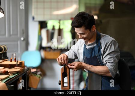 Lavoratore di pelli con un prodotto in pelle con cuciture ad ago in una morsa speciale. Concetto artigianale in pelle Foto Stock