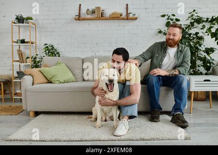 Due uomini con la barba seduti su un divano, godendosi momenti di qualità con il loro giocoso cane Labrador in un accogliente soggiorno. Foto Stock
