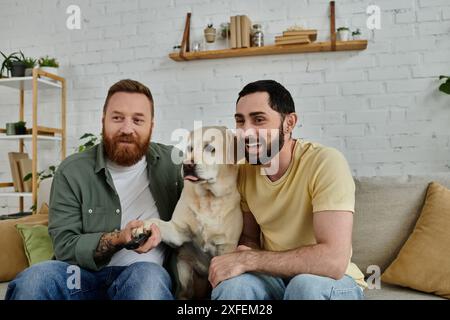 Coppia gay barbuta che si diverte con il loro amico peloso, un labrador, che si rilassa su un comodo divano a casa. Foto Stock