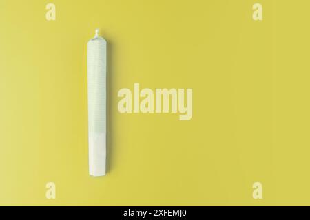 Preparazione del giunto di cannabis con tabacco e carta arrotolata con bocciolo di marijuana su sfondo giallo. L'insinuazione dell'abuso di marijuana. cannabis legaliza Foto Stock