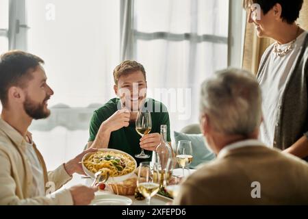 Una coppia gay ama cenare con i genitori a casa, creando ricordi caldi. Foto Stock