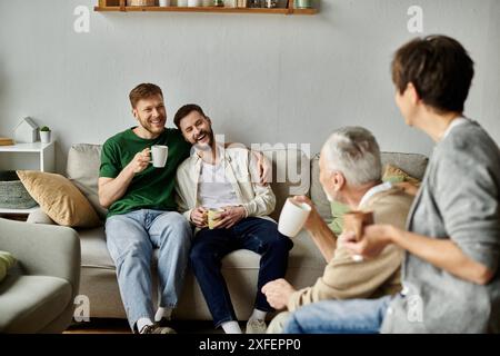 Una coppia gay ama il caffè con i genitori nel loro salotto. Foto Stock