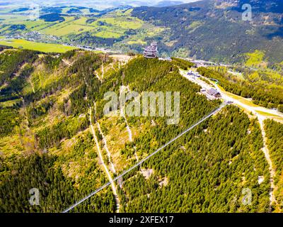 Vista aerea dello Sky Bridge 721, la passerella sospesa più lunga del mondo, che si estende su una montagna boscosa in Cechia. La torre panoramica Sky Walk si erge nelle vicinanze e offre vedute panoramiche Foto Stock